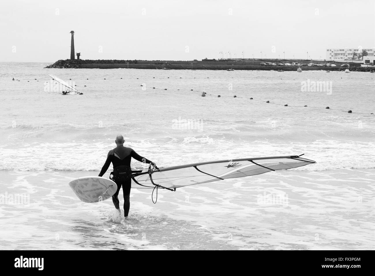 Ein Mann, der seinem Surfbrett ins Wasser Windsurfen, Surfen am Strand Costa Teguise Lanzarote, Spanien gesund leben, Lifestyle Konzept Stockfoto