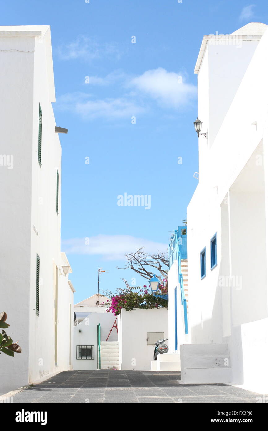 Die Seiten des Hohen hellen weißen Steinwänden Futter eine Spanische Straße an einem sonnigen Tag auf Lanzarote vor blauem Himmel Stockfoto