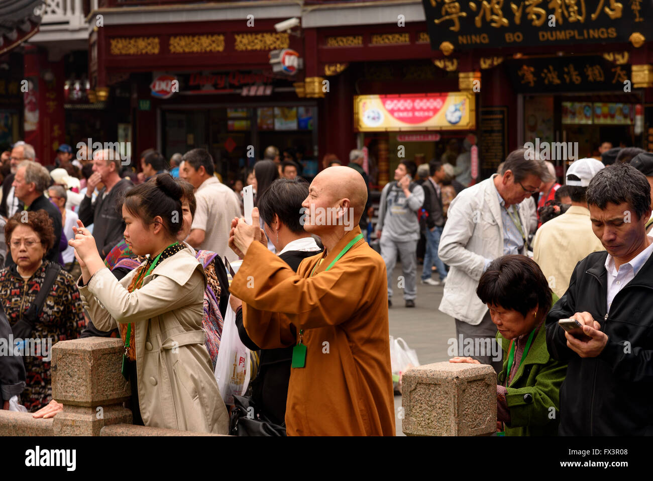ein Mönch gekleidet in orangefarbenen Gewändern unter Menschenmenge, Fotos Sehenswürdigkeiten auf Handy Stockfoto