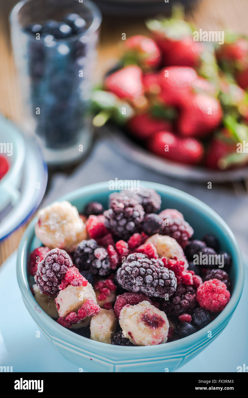 Gefrorene Beeren, Smoothie Zutaten. In pulsierende blaue Schüssel auf Holztisch Stockfoto