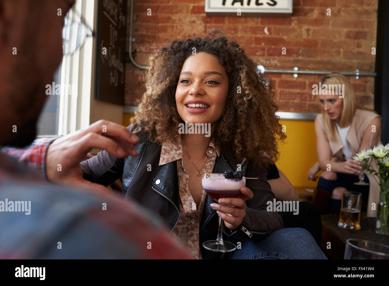 Junges Paar genießen Drink In belebten Cocktail Bar Stockfoto