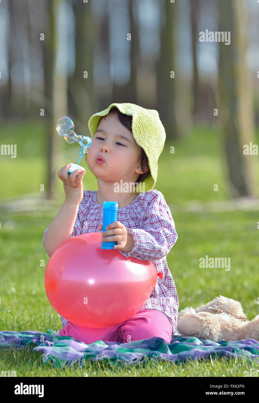 kleines Mädchen bläst ein Seifenblasen im Wald Stockfoto