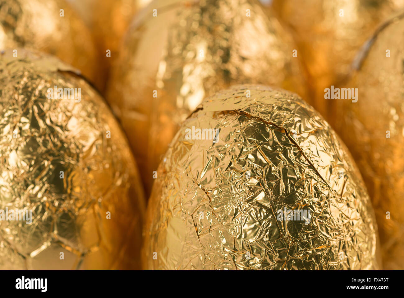 über Nachsicht in Schokolade Ostereier eingewickelt in glänzender Goldfolie in Reihen bereit für Schokoholiker Übergewicht Gesundheitsproblem Stockfoto