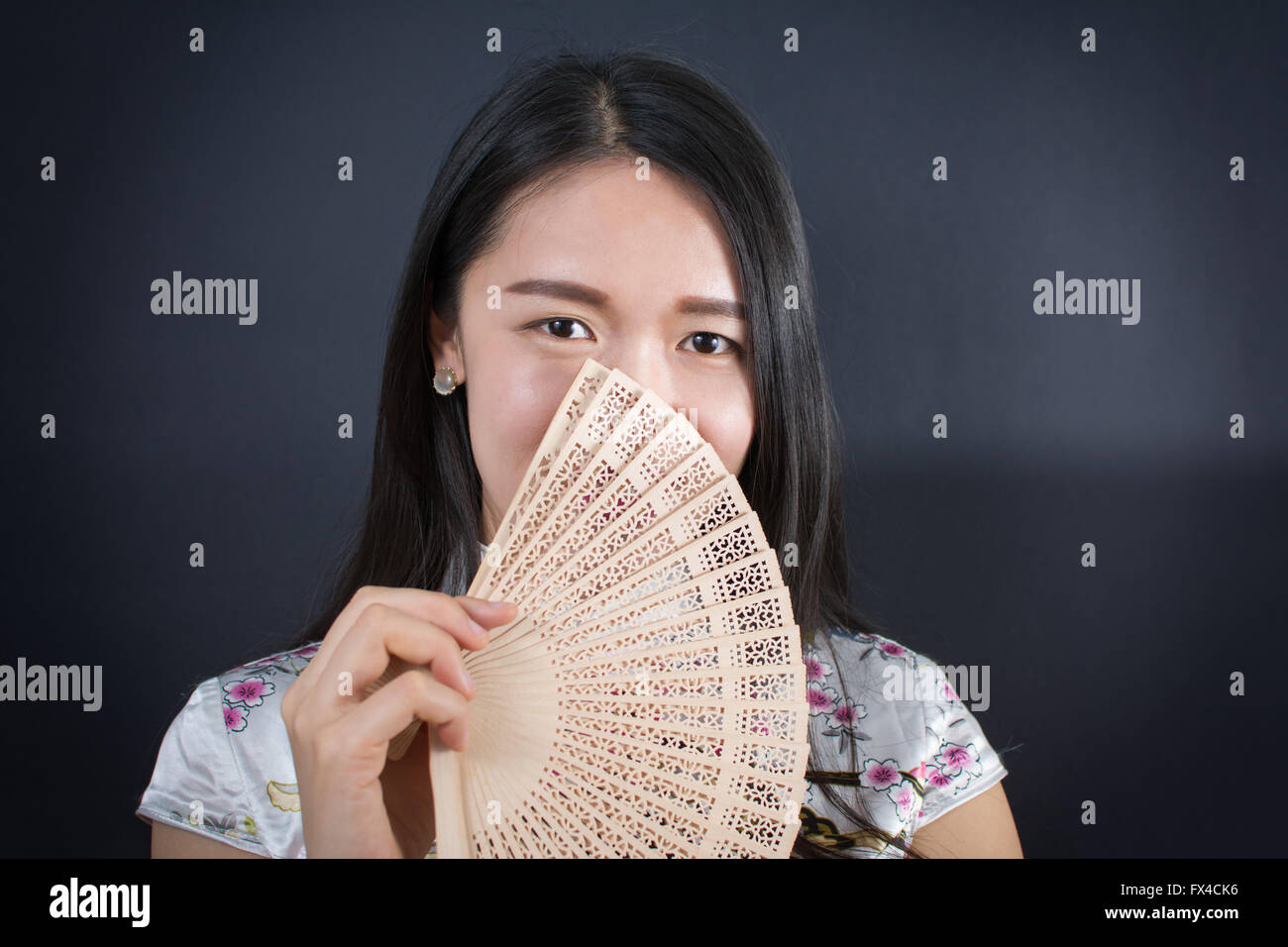 Schöne asiatische Frau hält einen Handventilator Stockfoto