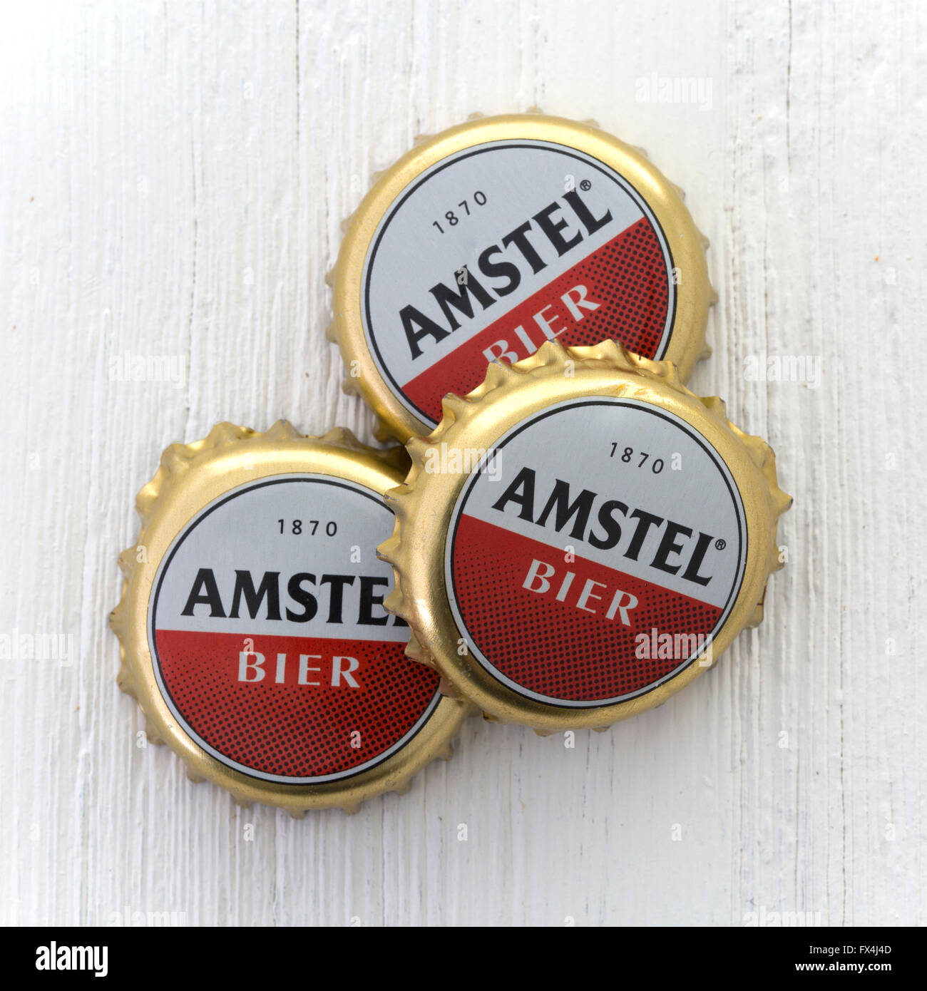 Drei Kronkorken von Amstel Bier auf einem weißen Hintergrund Holz Stockfoto
