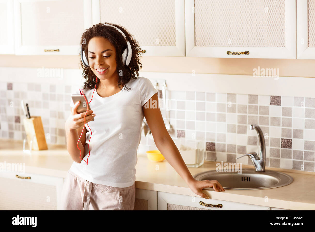 Schöne Mädchen anhören von Musik in der Küche Stockfoto