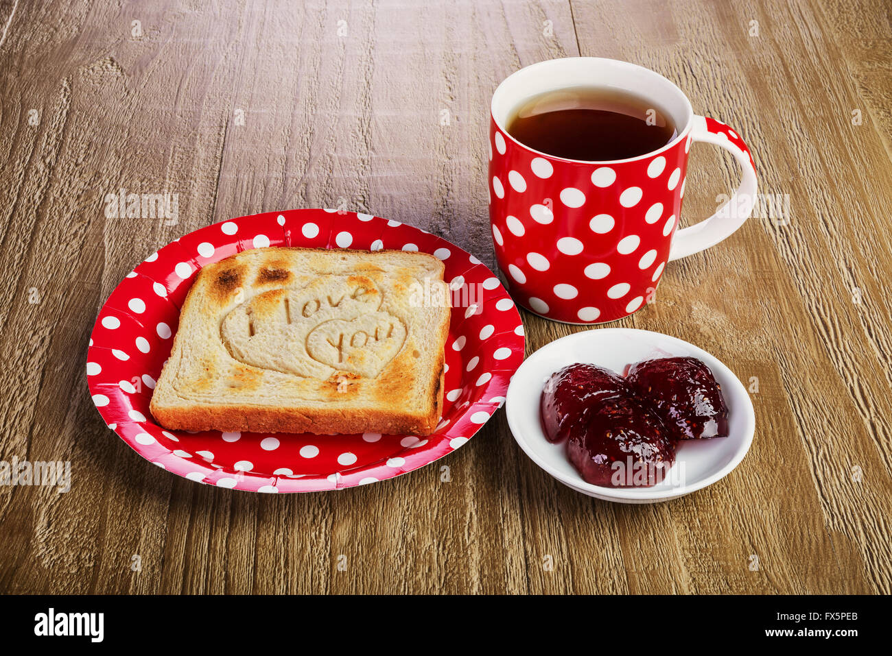 geröstetes Brot mit Liebesbotschaft und Himbeermarmelade und Tee. Frühstück für einen lieben Menschen Stockfoto