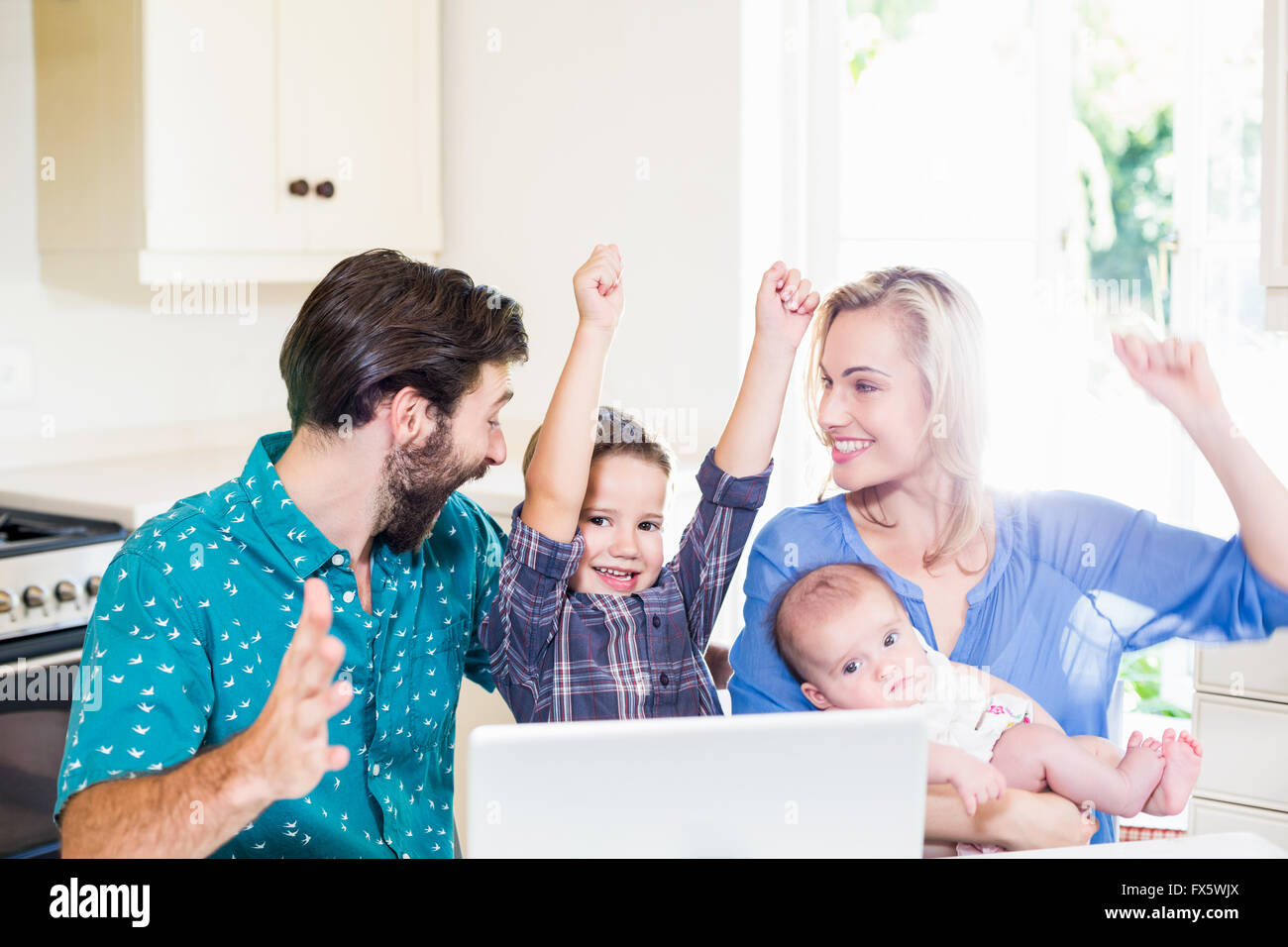 Begeistert Eltern und Kinder mit Laptop in der Küche Stockfoto
