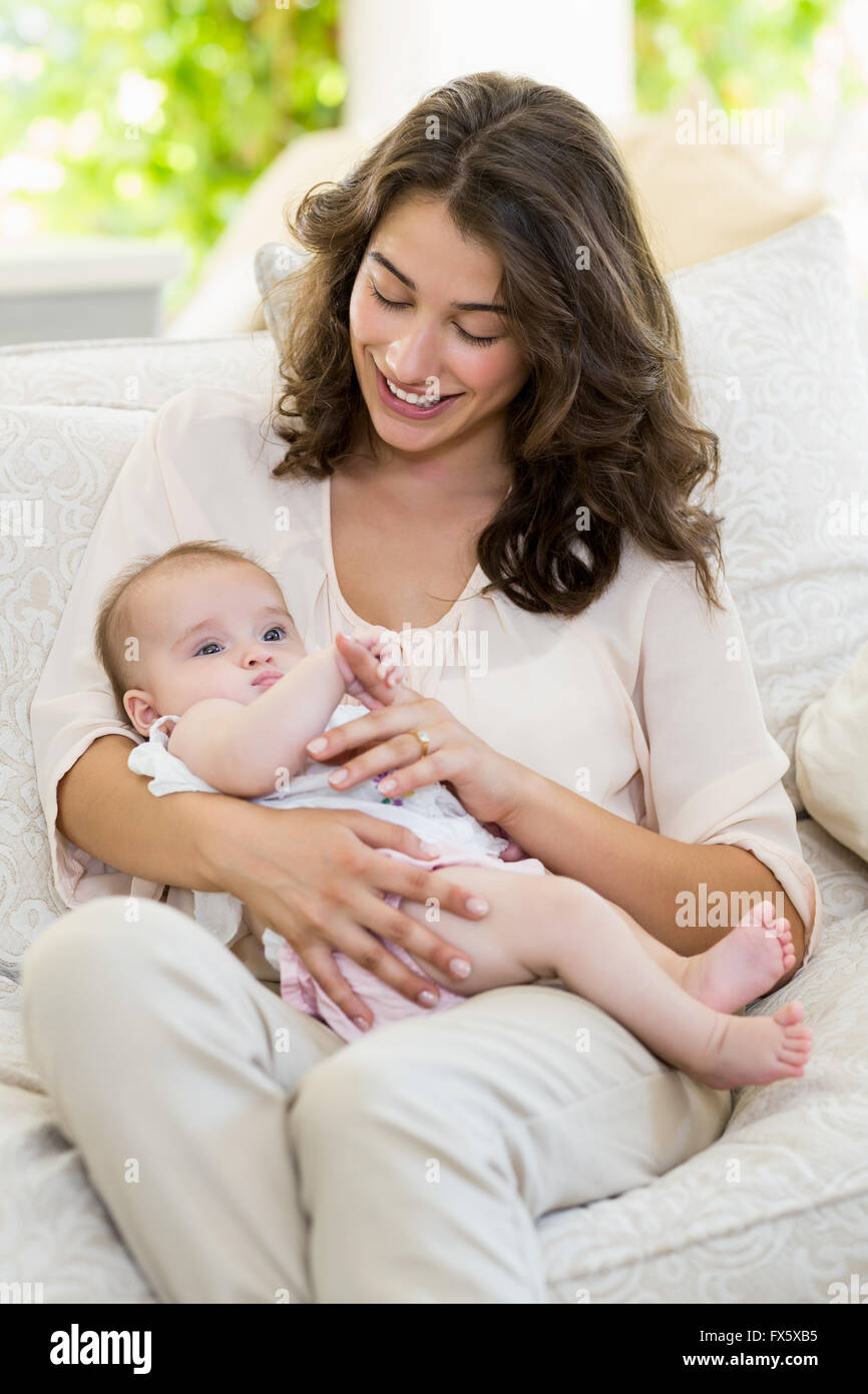 Mutter hält ihr Baby auf Schoß im Wohnzimmer Stockfoto