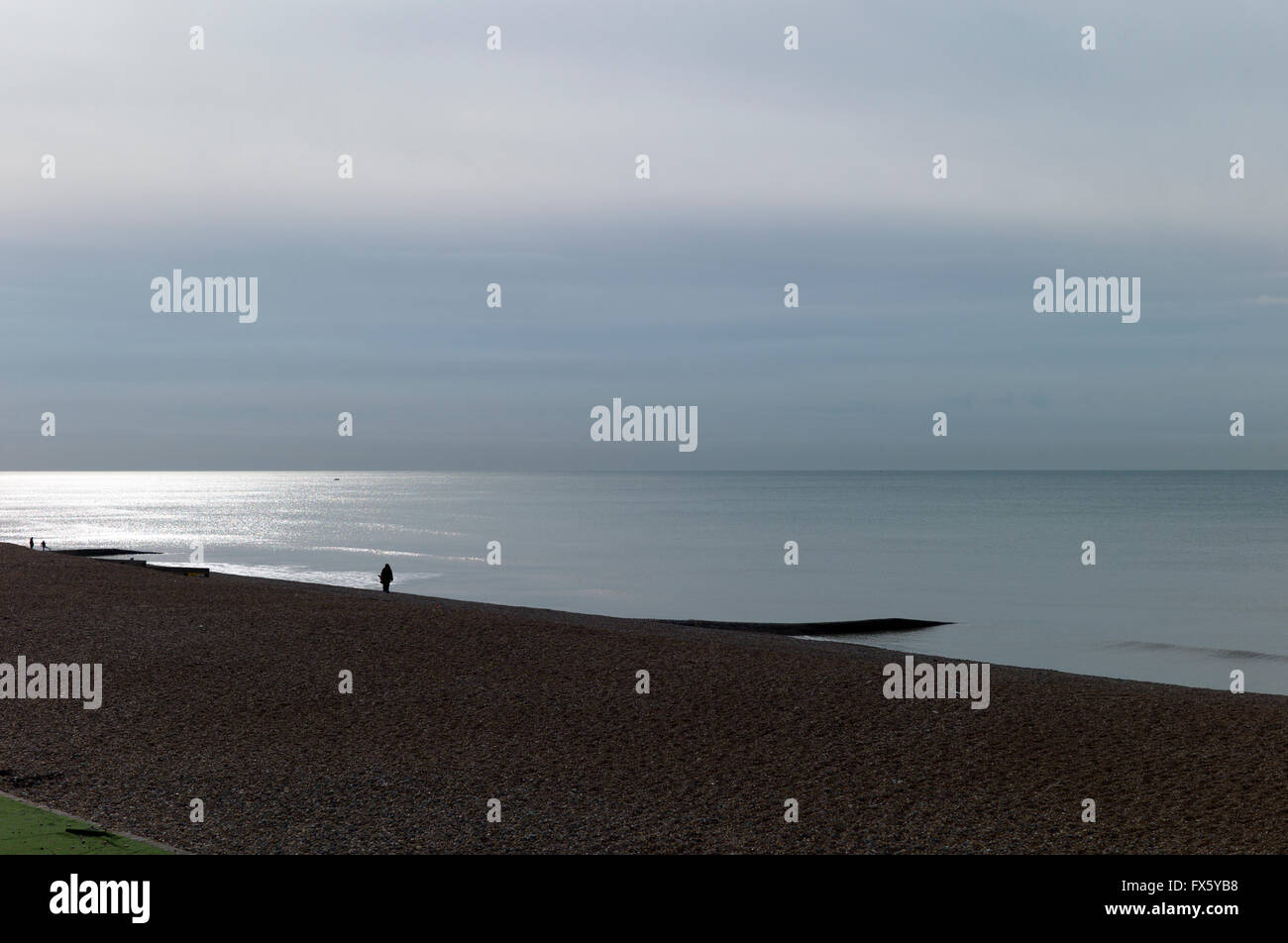 Einsame Figur in der Silhouette am leeren Strand, ruhige See, Brighton Stockfoto