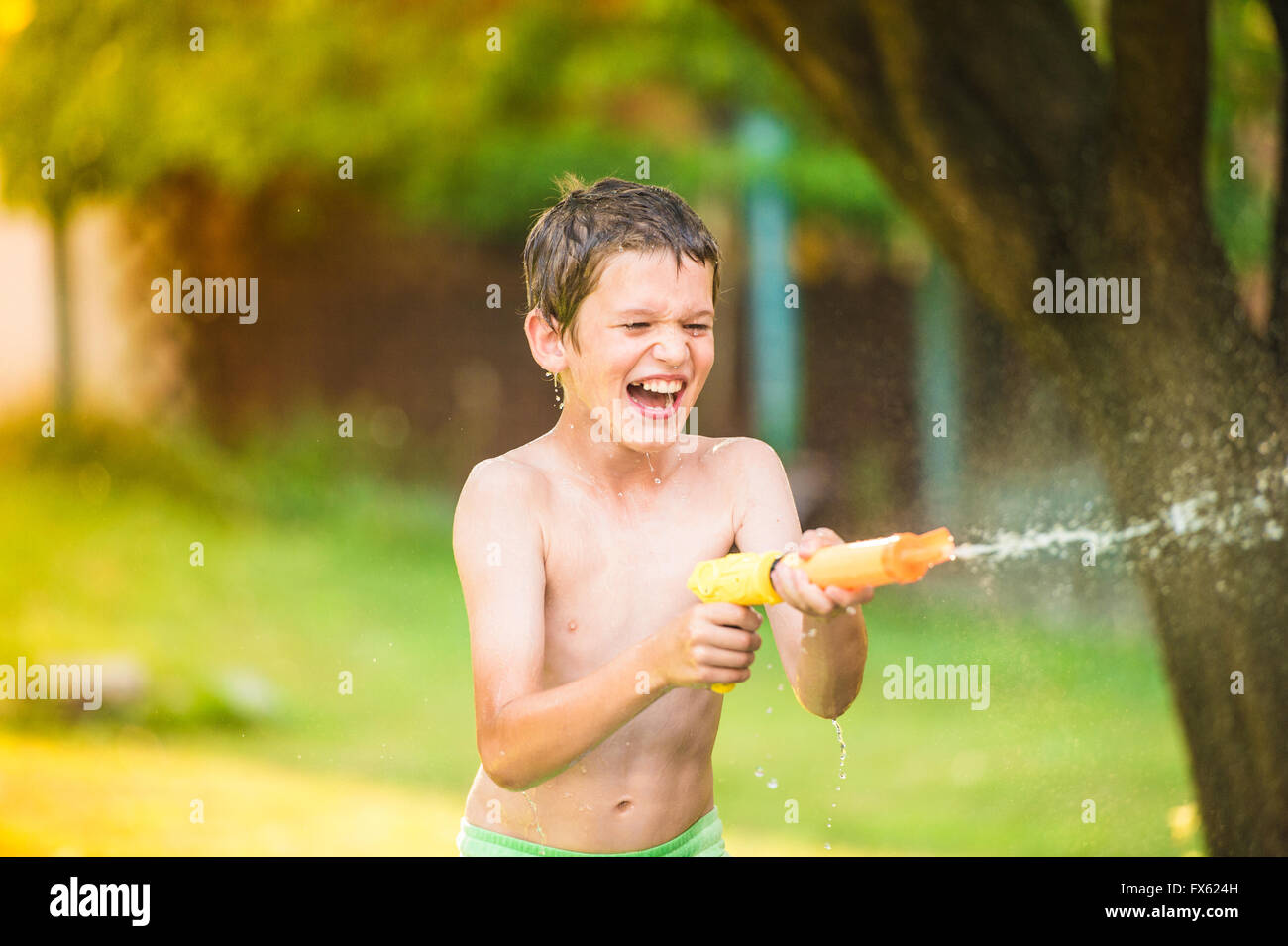 Junge Kinder mit Wasserpistole, sonniger Sommergarten Spritzen Stockfoto