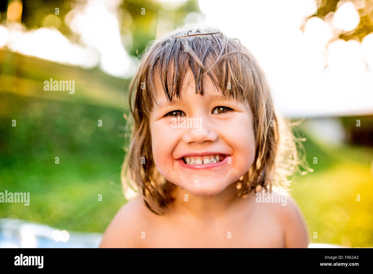 Niedliche kleine lächelnde Mädchen im sonnigen Garten Stockfoto