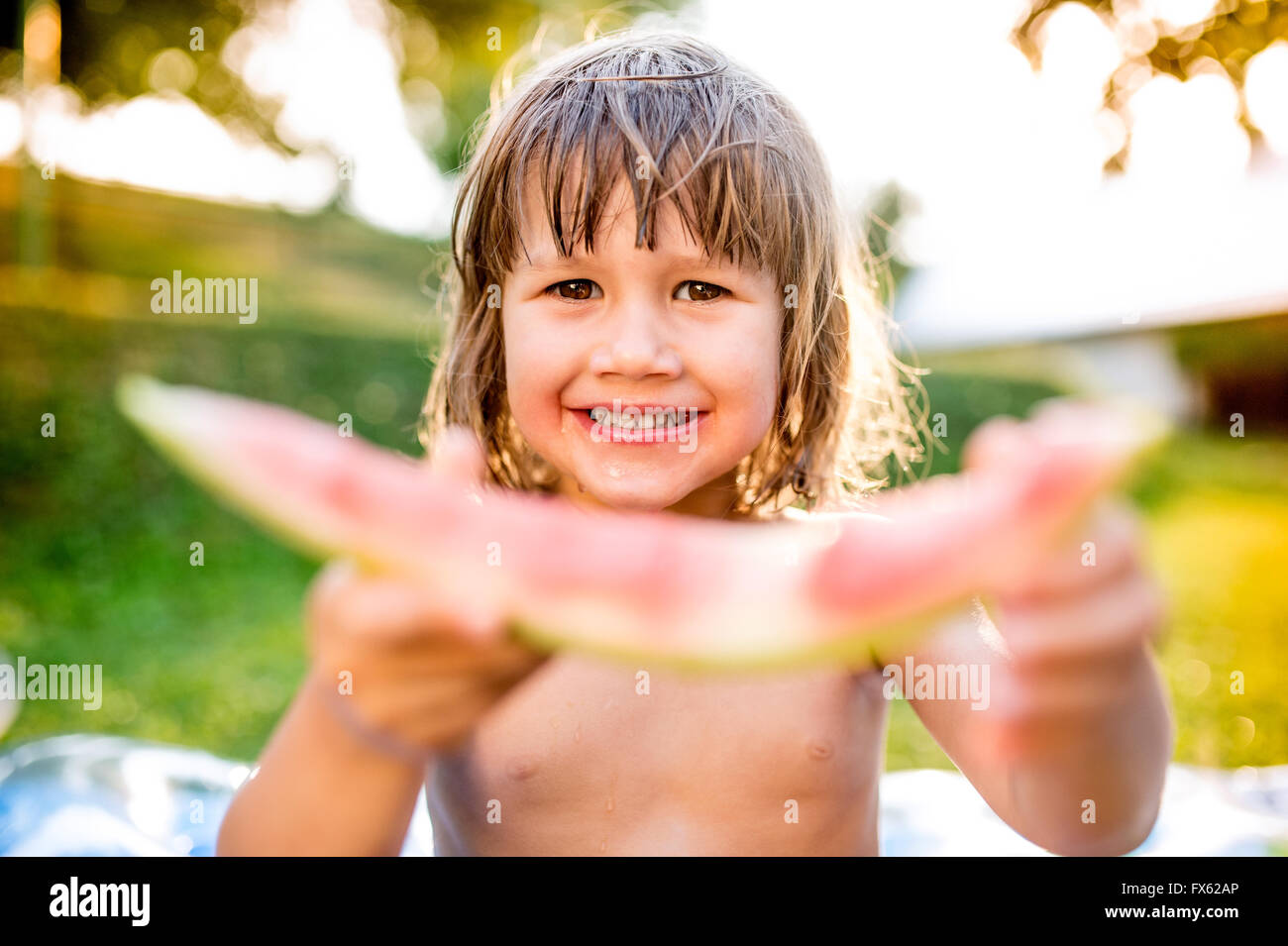 Niedliche kleine Mädchen essen Wassermelone in sonniger Sommergarten Stockfoto