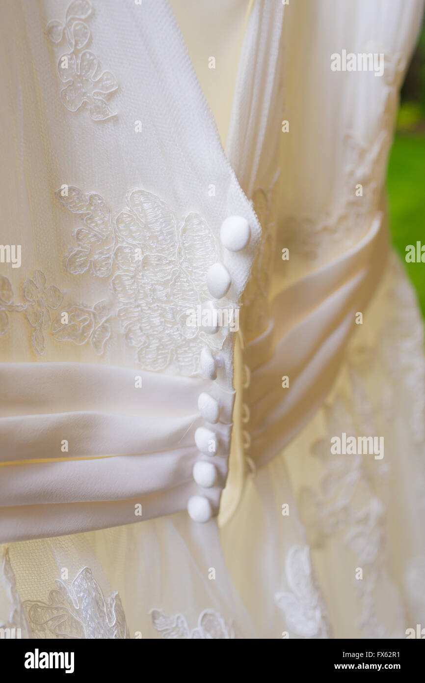 Weißes Brautkleid vor einer Zeremonie draußen hängen. Stockfoto