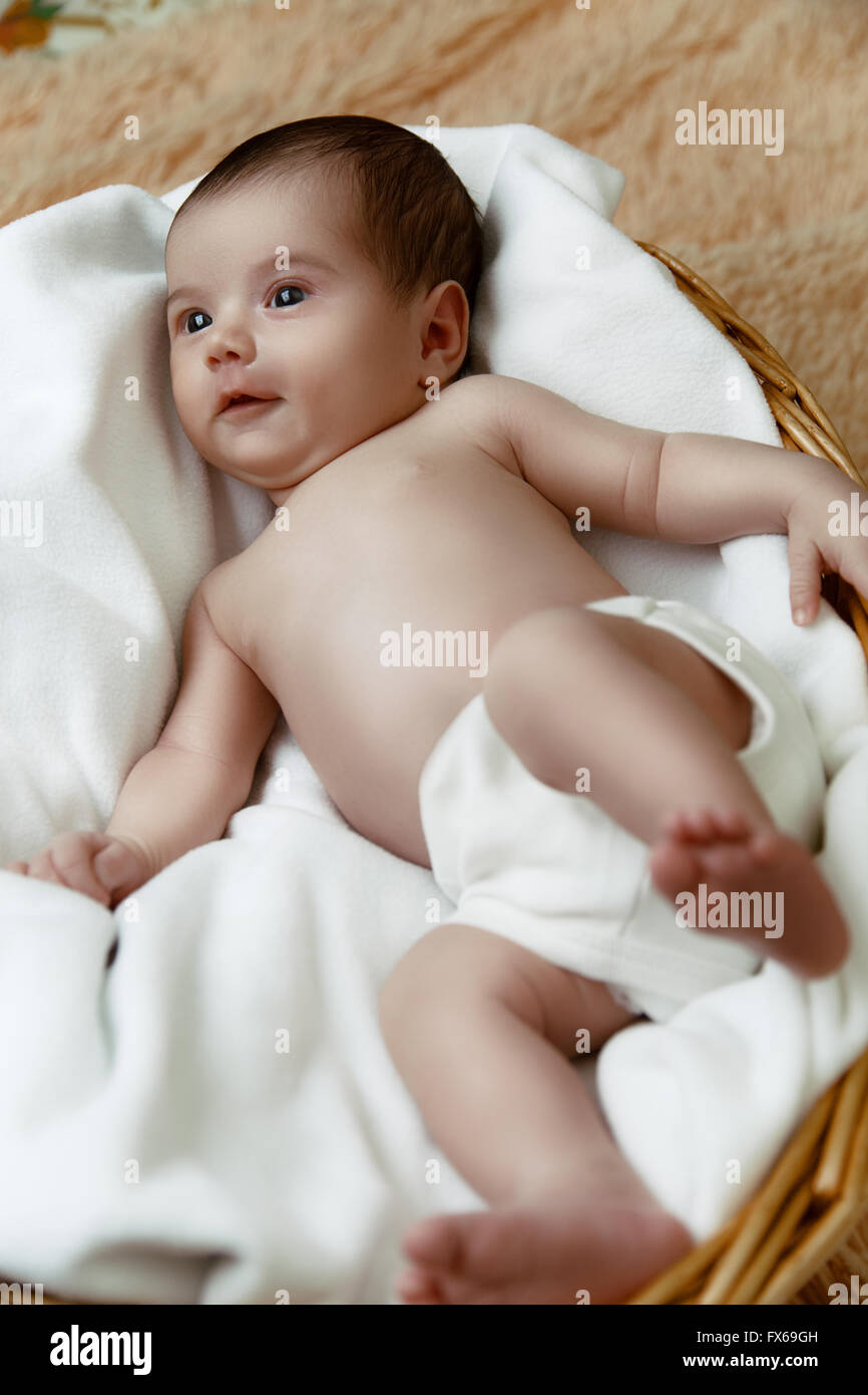 Lächelnde neugeborenes Baby liegend im Weidenkorb Stockfoto