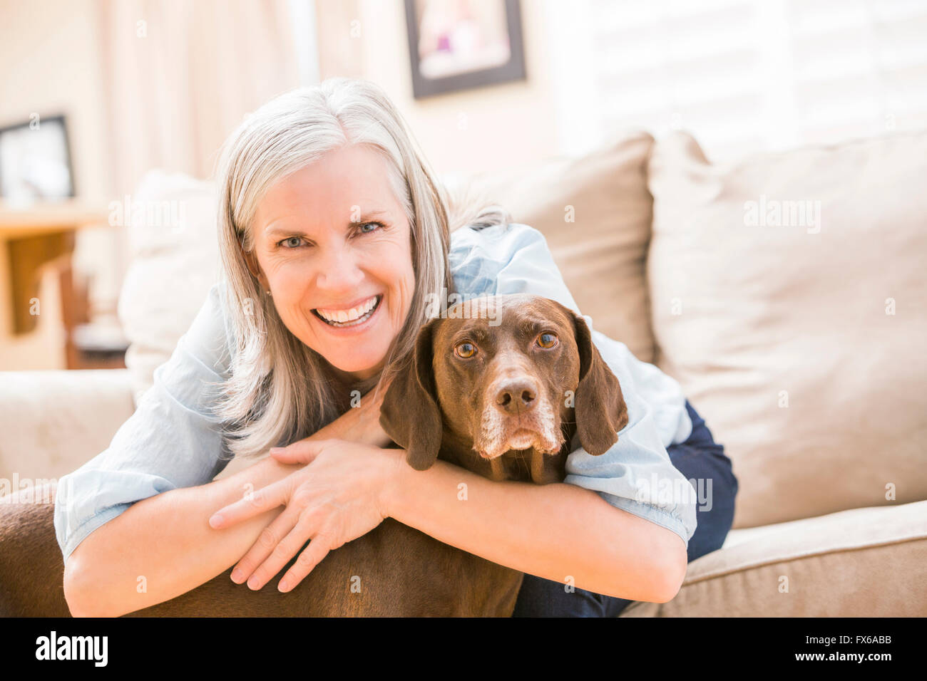 Kaukasische Frau umarmt Hund auf sofa Stockfoto