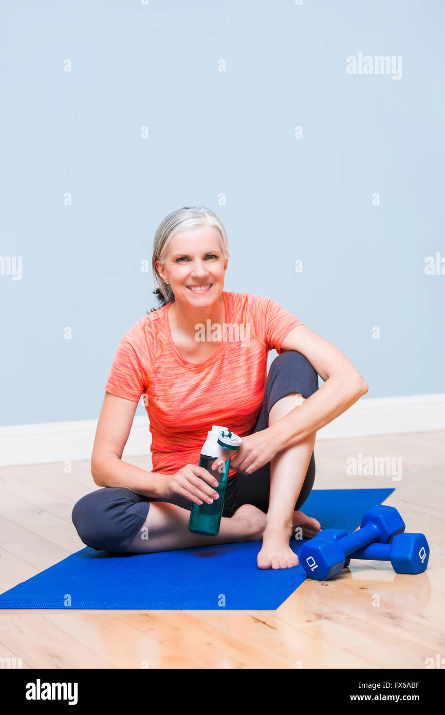 Kaukasische Frau Trinkwasser auf Yoga-Matte Stockfoto