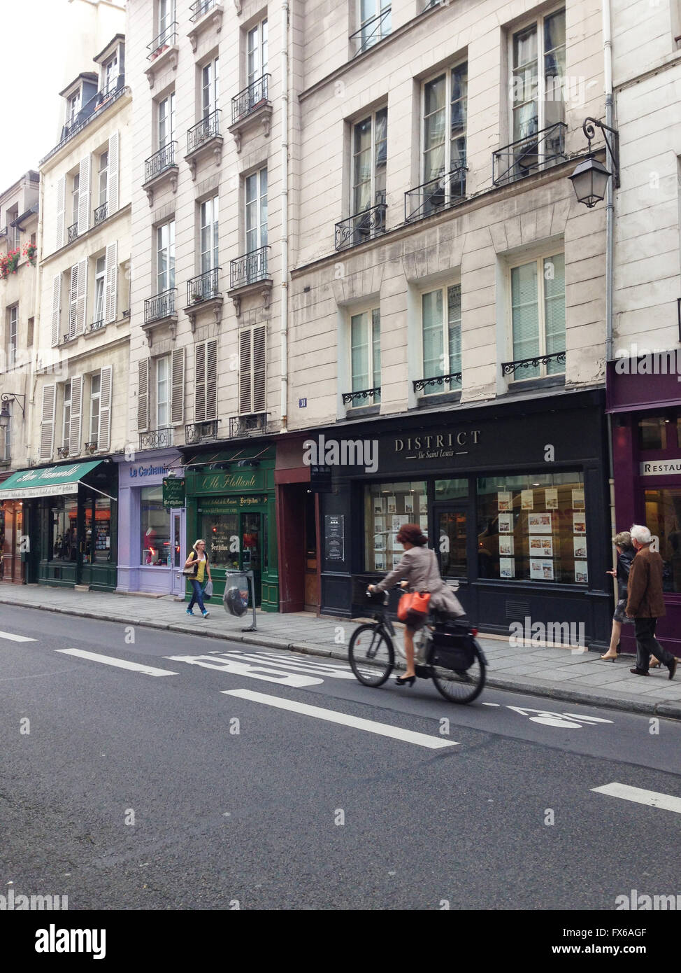 Frau reitet auf einem Fahrrad und einige Passanten in der Straße im Viertel Saint Germain in Paris Stockfoto
