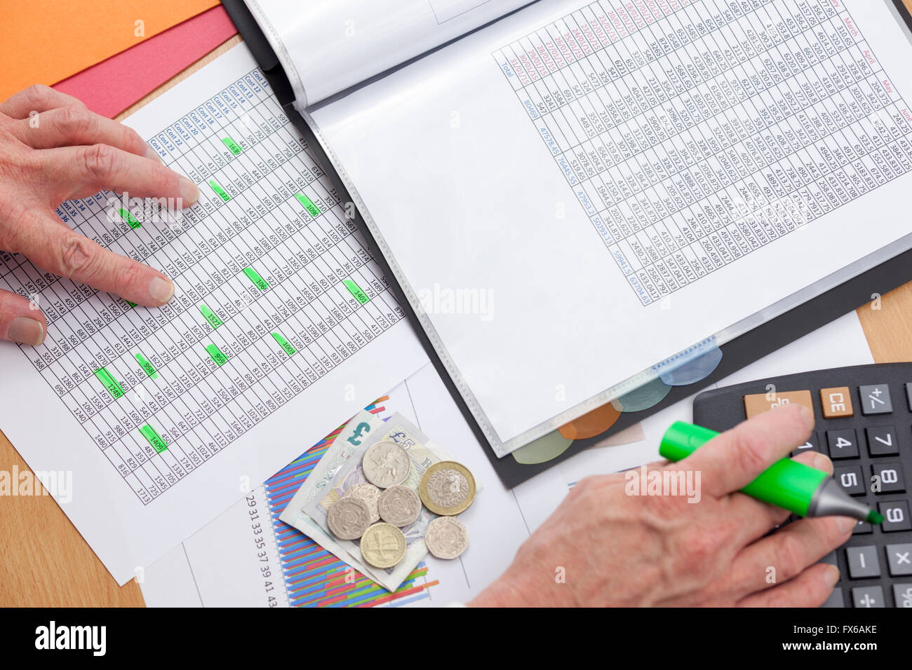 Beschäftigt Finanzier an seinem Schreibtisch mit einen Taschenrechner, einen Umsatzbericht mit Bargeld lose Verlegung oberste Sicherheitsebene eines Diagramms zu überprüfen Stockfoto