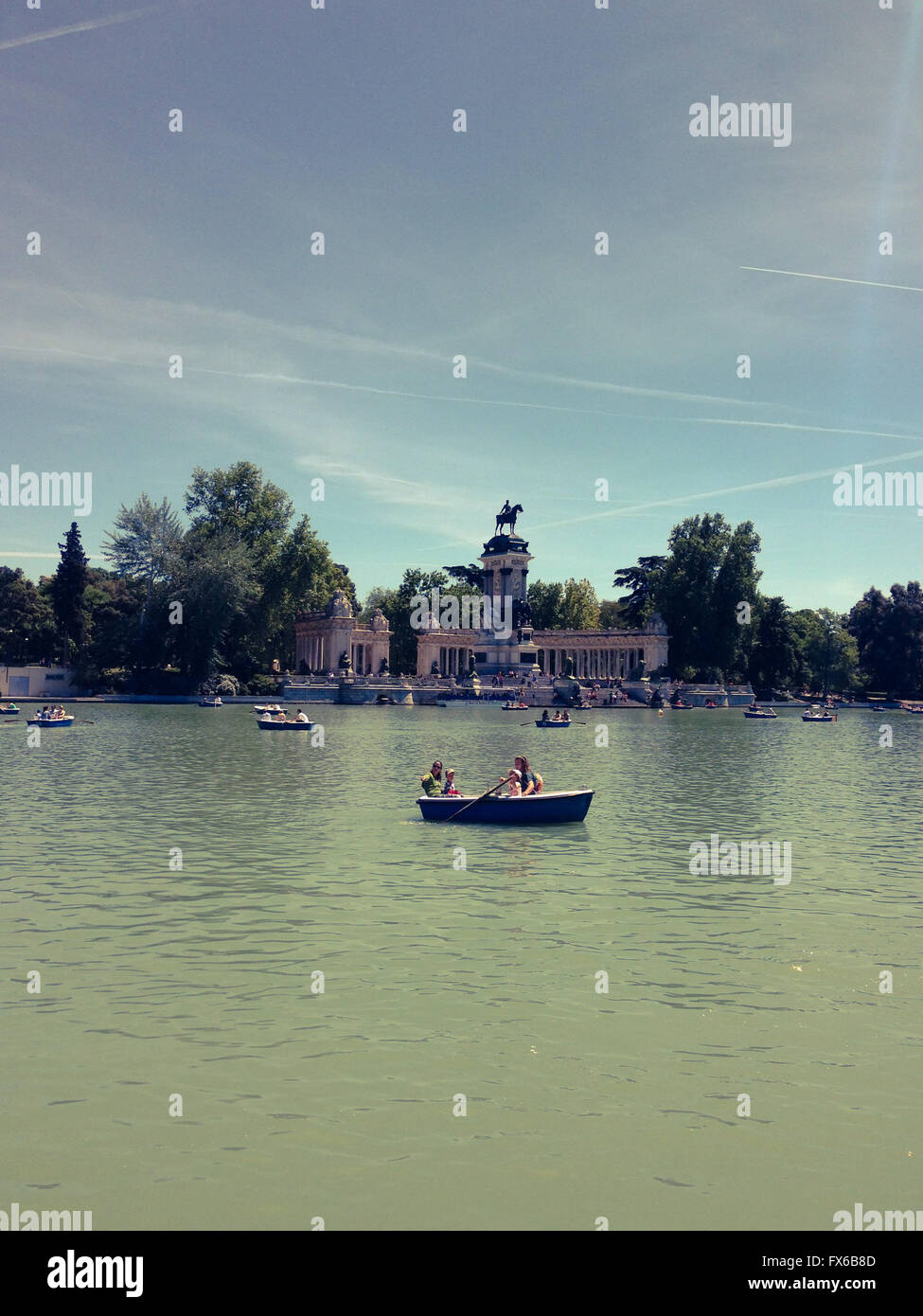 Menschen fahren Boote auf einem künstlichen See vor König Alfonso XII Denkmal im El Retiro Park in Madrid Stockfoto