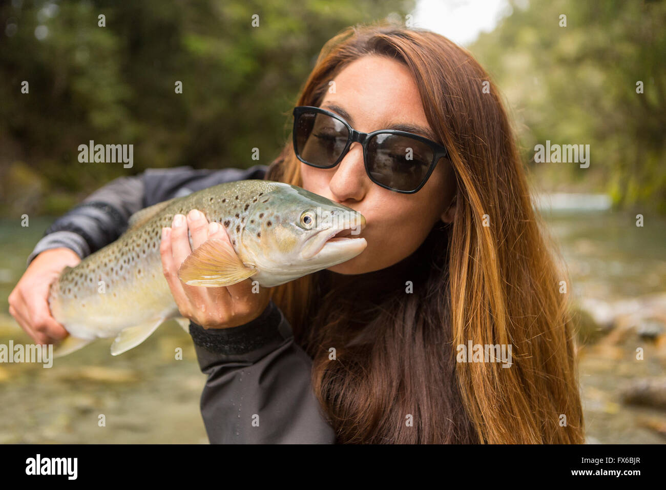 Kaukasische Frau küssen Fische in abgelegenen Fluss Stockfoto