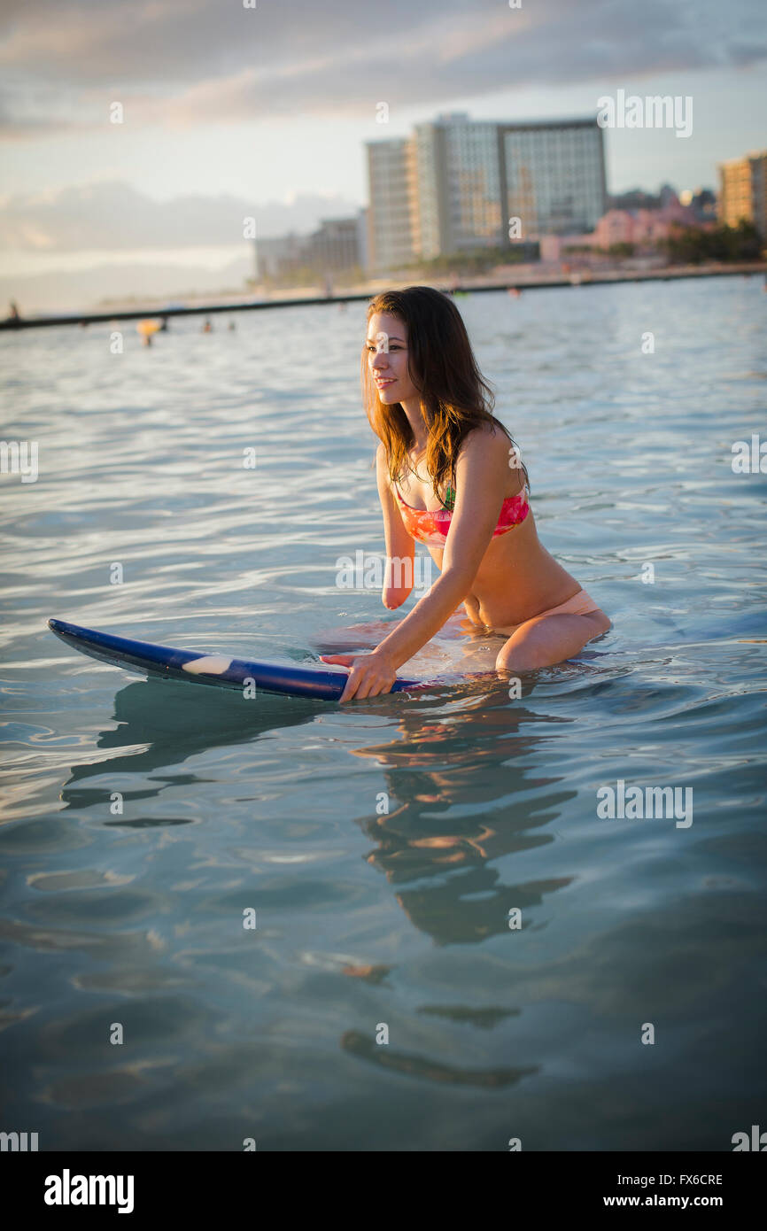 Gemischte Rassen Amputierte sitzen auf Surfbrett im Ozean Stockfoto