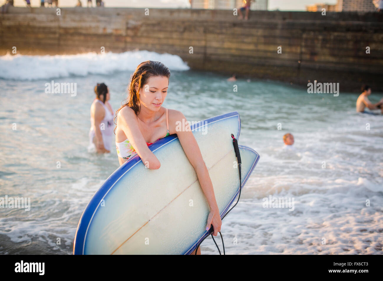 Gemischte Rassen Amputierte Surfbrett am Strand tragen Stockfoto