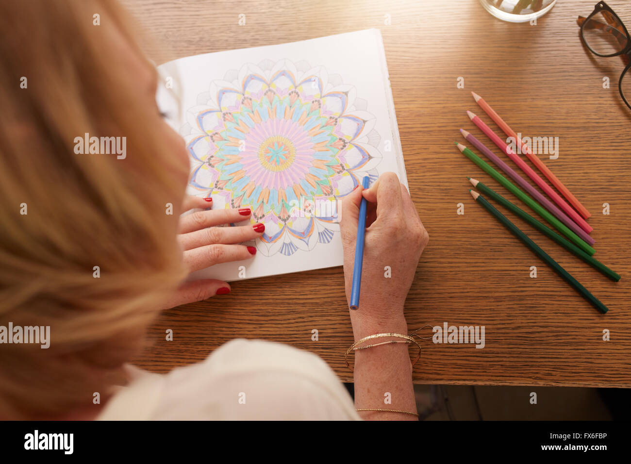 Draufsicht der Frau in Erwachsene Malbuch mit Farbstiften zeichnen. Anti-Stress zu Hause ausüben. Stockfoto