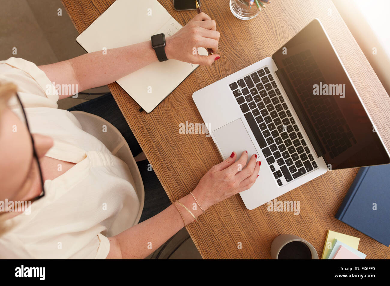 Draufsicht der Frau an ihrem Schreibtisch sitzen und arbeiten am Laptop. Geschäftsfrau, arbeiten von zu Hause aus. Stockfoto