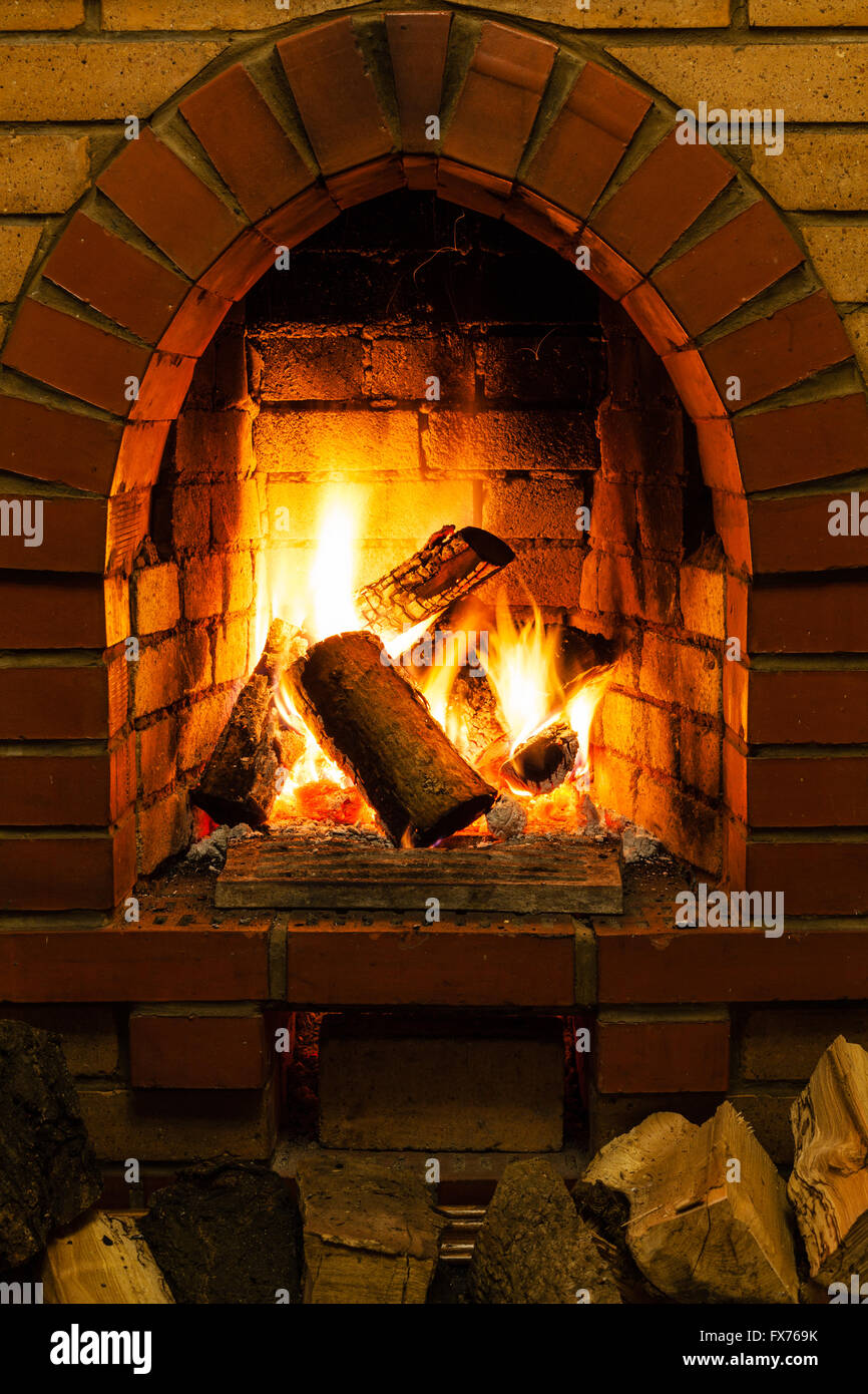 Brennholz und Zungen des Feuers im Kamin im Landhaus Stockfoto