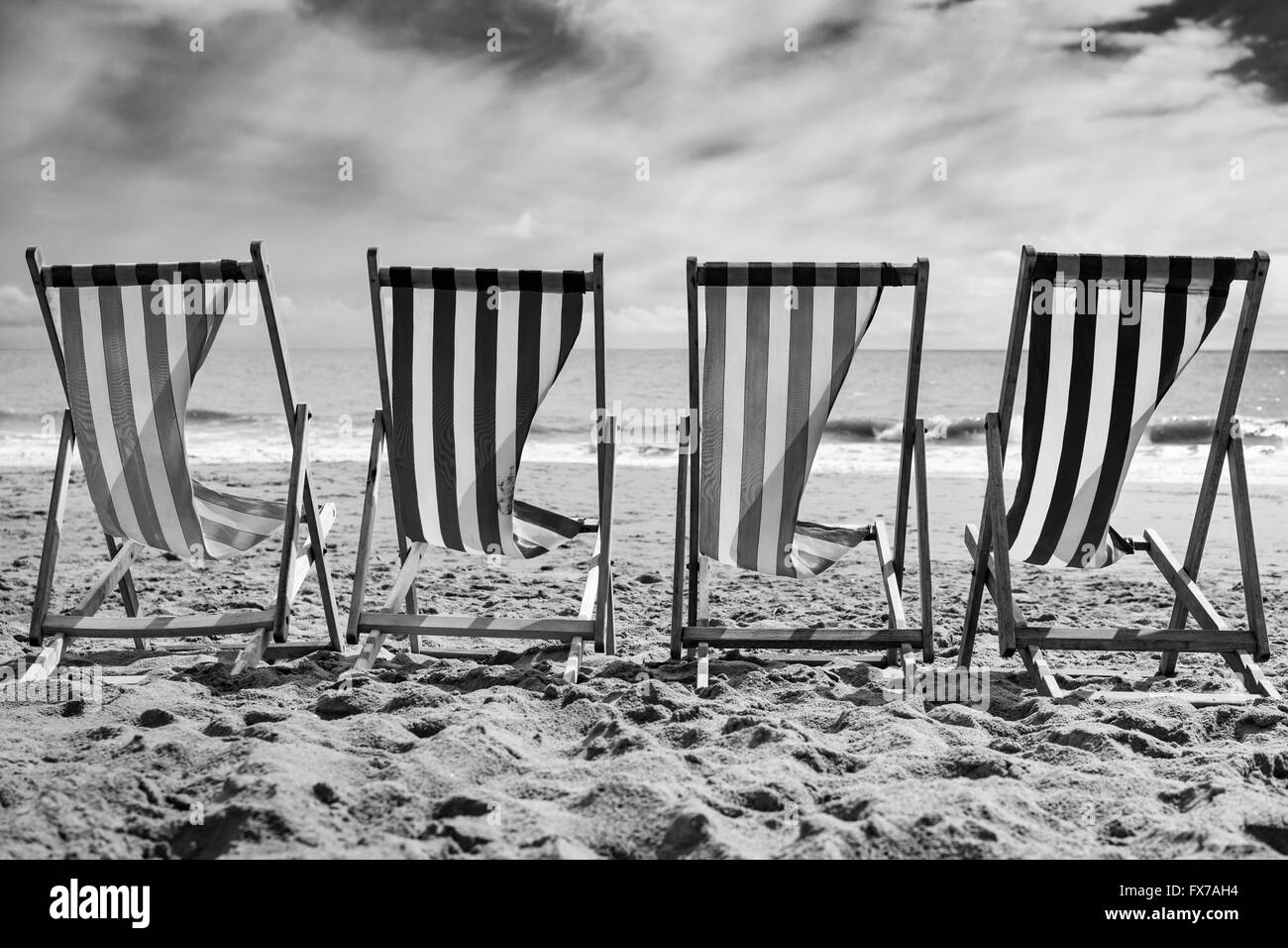 Eine Reihe von 4 gestreifte Liegestühle im Wind am Strand von Bournemouth, UK Stockfoto