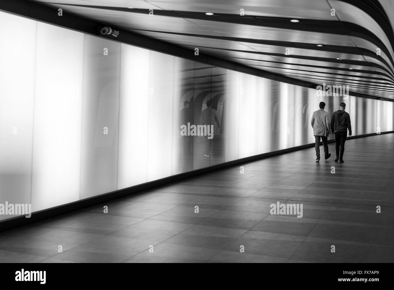 Zwei Männer zu Fuß entlang der LED beleuchteten Tunnel zwischen Kings cross / St. Pancras, One St Pancras Square Stockfoto