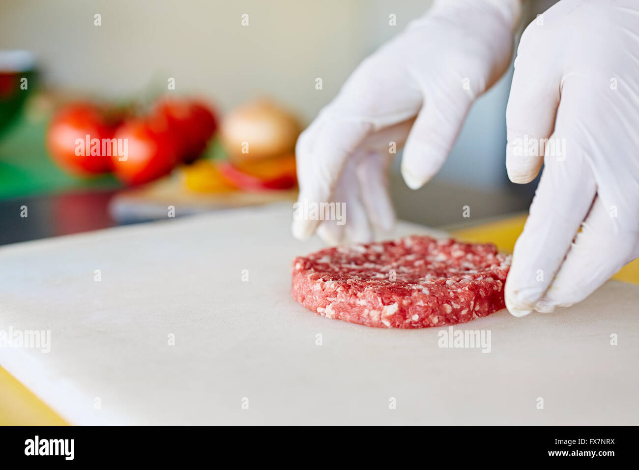 Hände in weißen Handschuhen Prearing einem frischen Hamburger patty Stockfoto