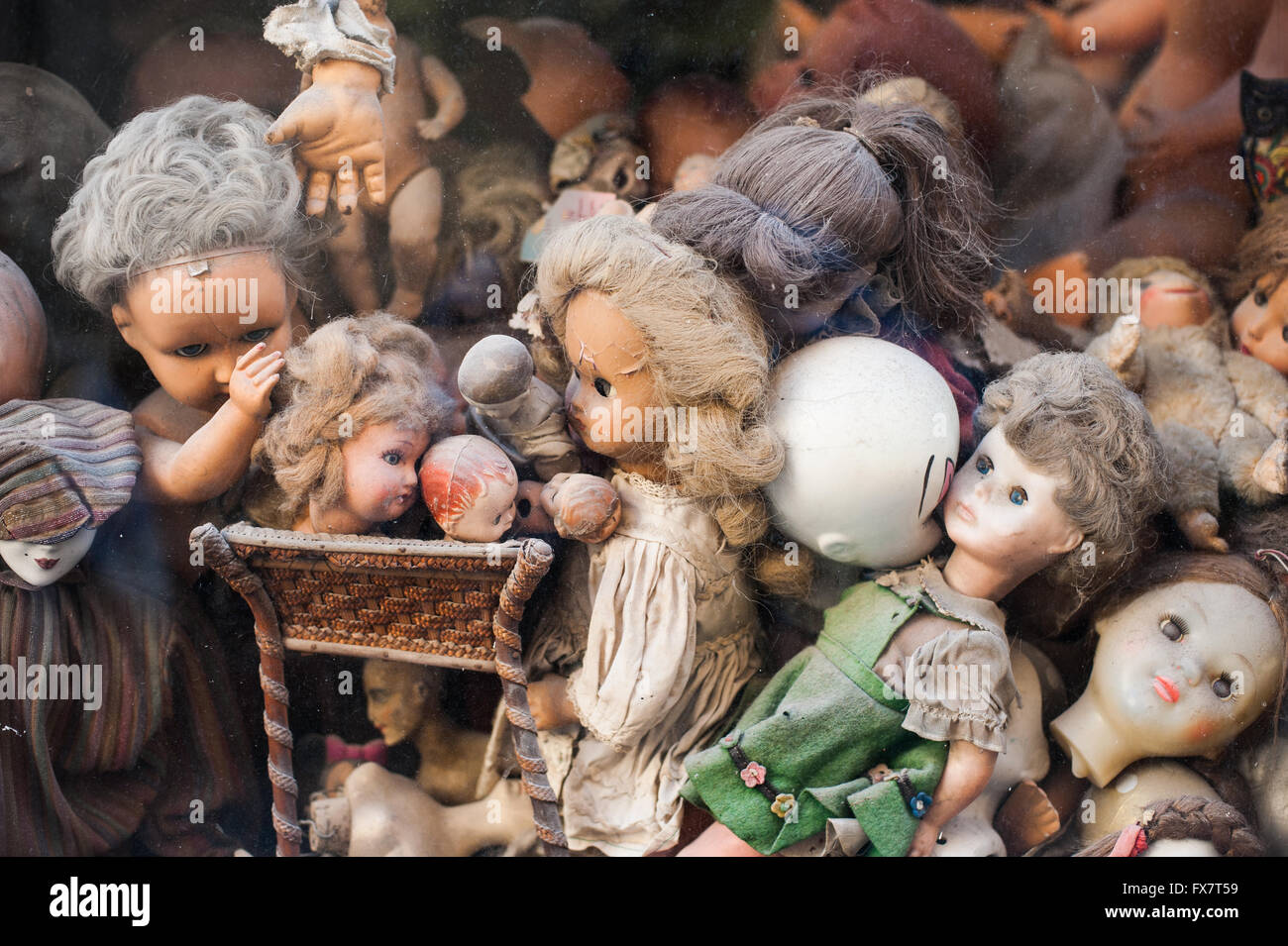 Viele antike zerbrochene Puppe Blick aus einem Schaufenster Stockfoto