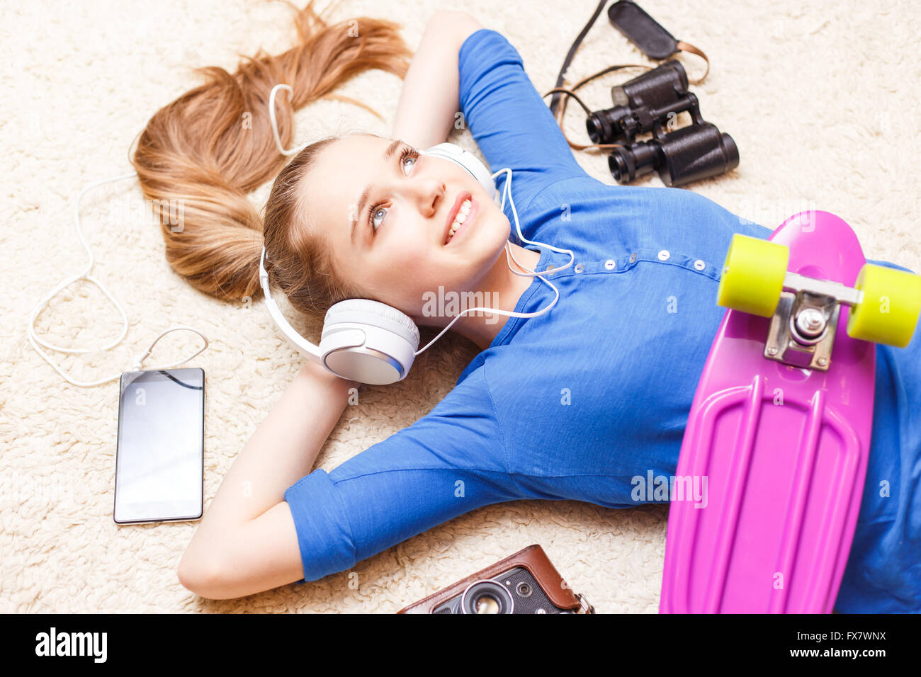 Träumen fröhliche Teenager-Mädchen auf dem Boden liegend mit Penny Board Kamera Telefon Fernglas. Glücklich Teenager Mädchen träumen von t Stockfoto
