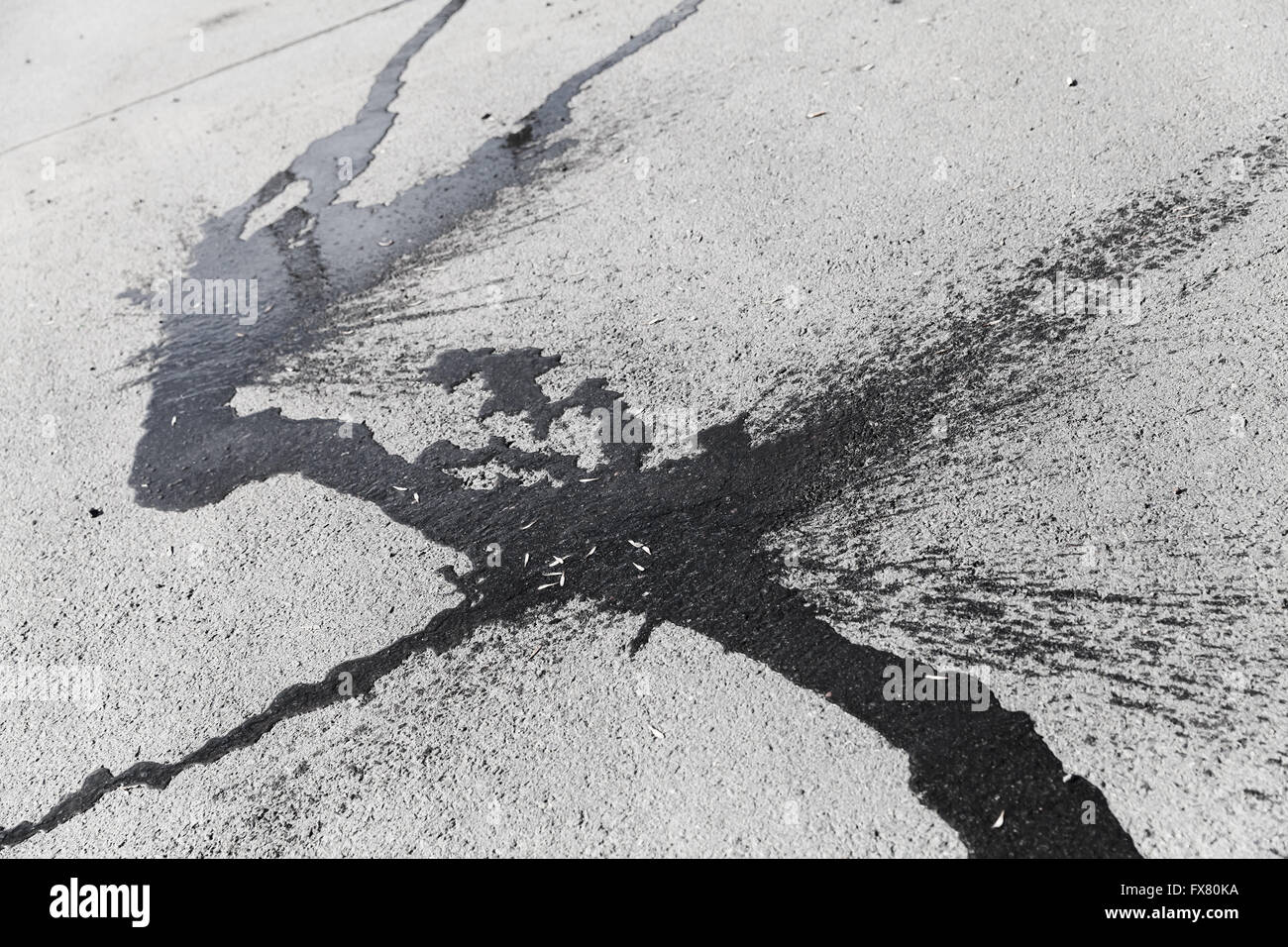 Abstrakt geformte dunkle Spritzwasser auf trockenen grauen städtischen Asphaltdecke Stockfoto