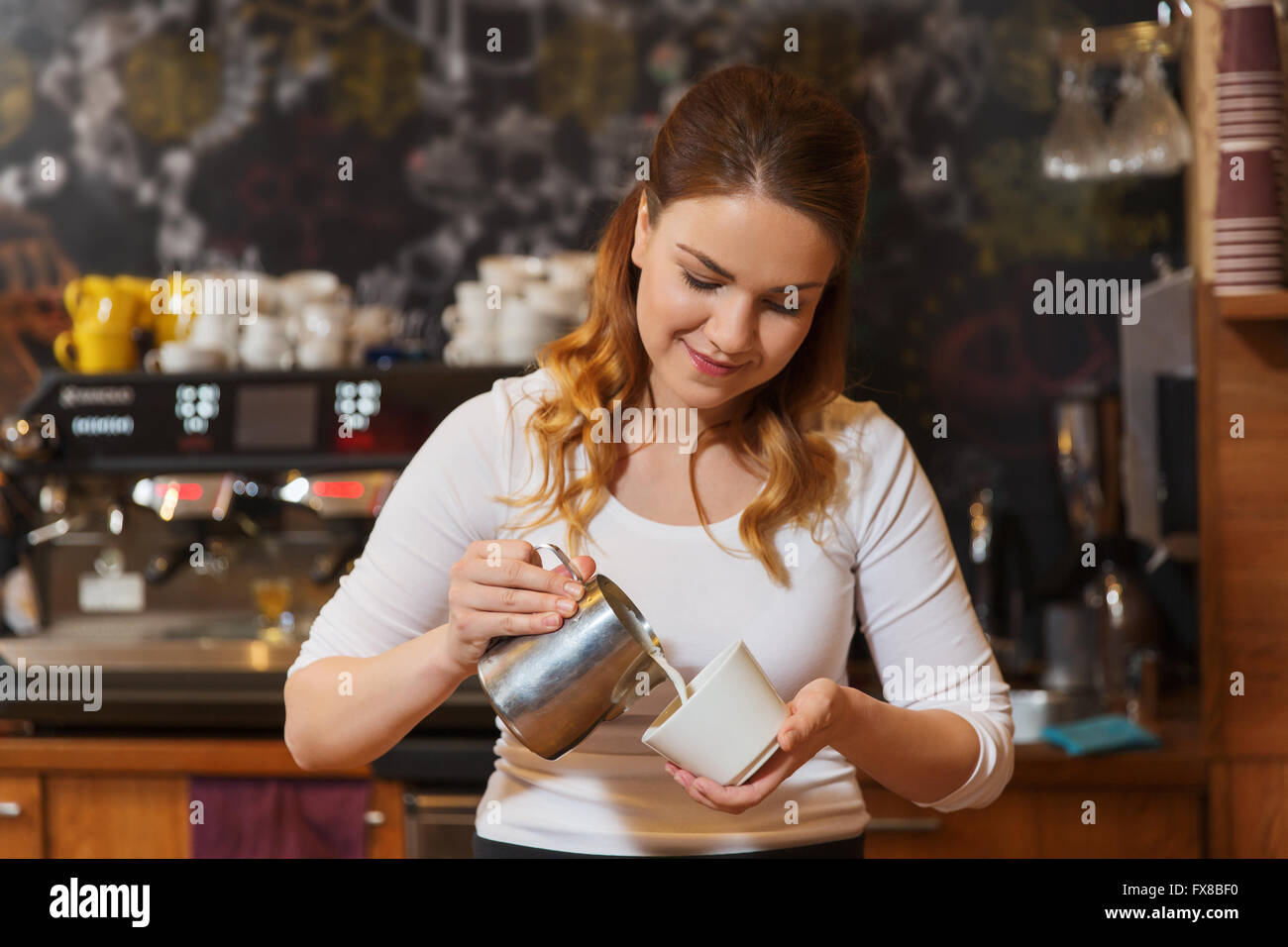 Barista Frau gießt Sahne, Kaffeehaus Stockfoto