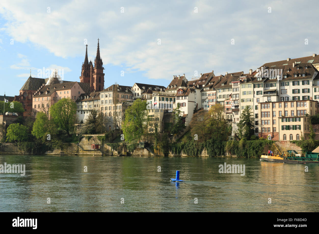 Ein Foto von einem Schiff nähert sich der Kathedrale auf dem Rhein in Basel, Schweiz. Auch bekannt als das Basler Münster Stockfoto