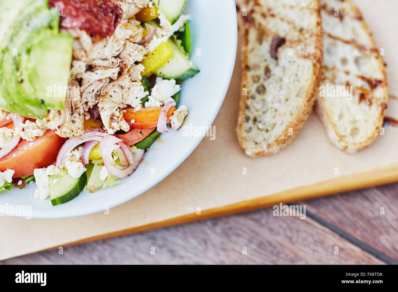 Bunter Salat mit frischen Zutaten neben geschnittenem Brot Stockfoto