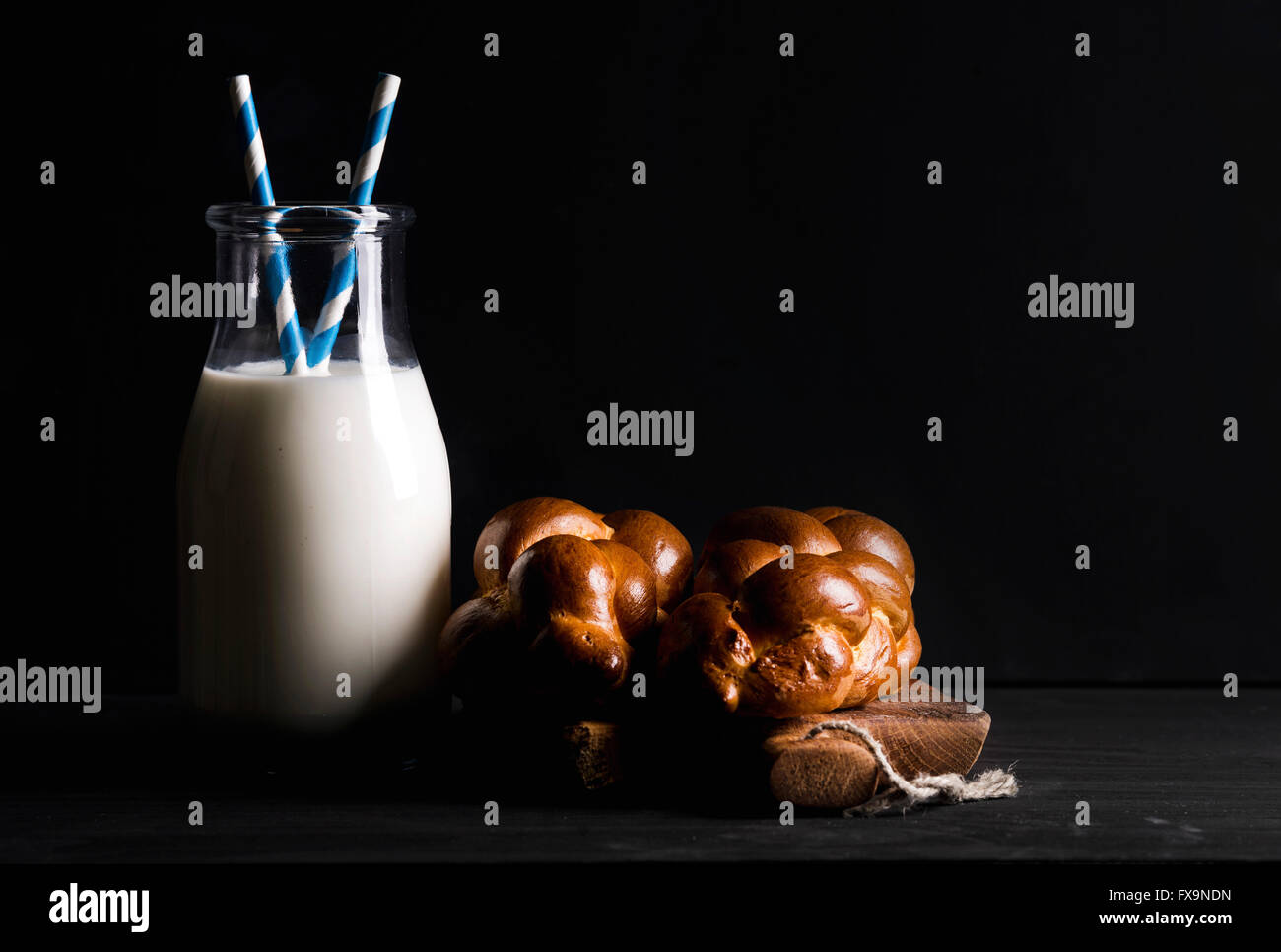 Flasche Milch und Milch Brot Brötchen auf rustikalem Holzbrett auf dunklem Hintergrund, selektiven Fokus Stockfoto