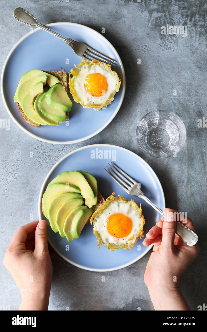 Gebackenen Eiern in Kartoffel Nester mit Avocado-toast Stockfoto