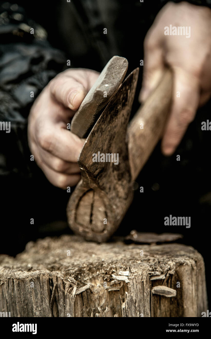 Nahaufnahme von männlichen Händen schärfen schmutzige alte rostige Axt mit einem Schleifstein auf Baumstumpf Stockfoto
