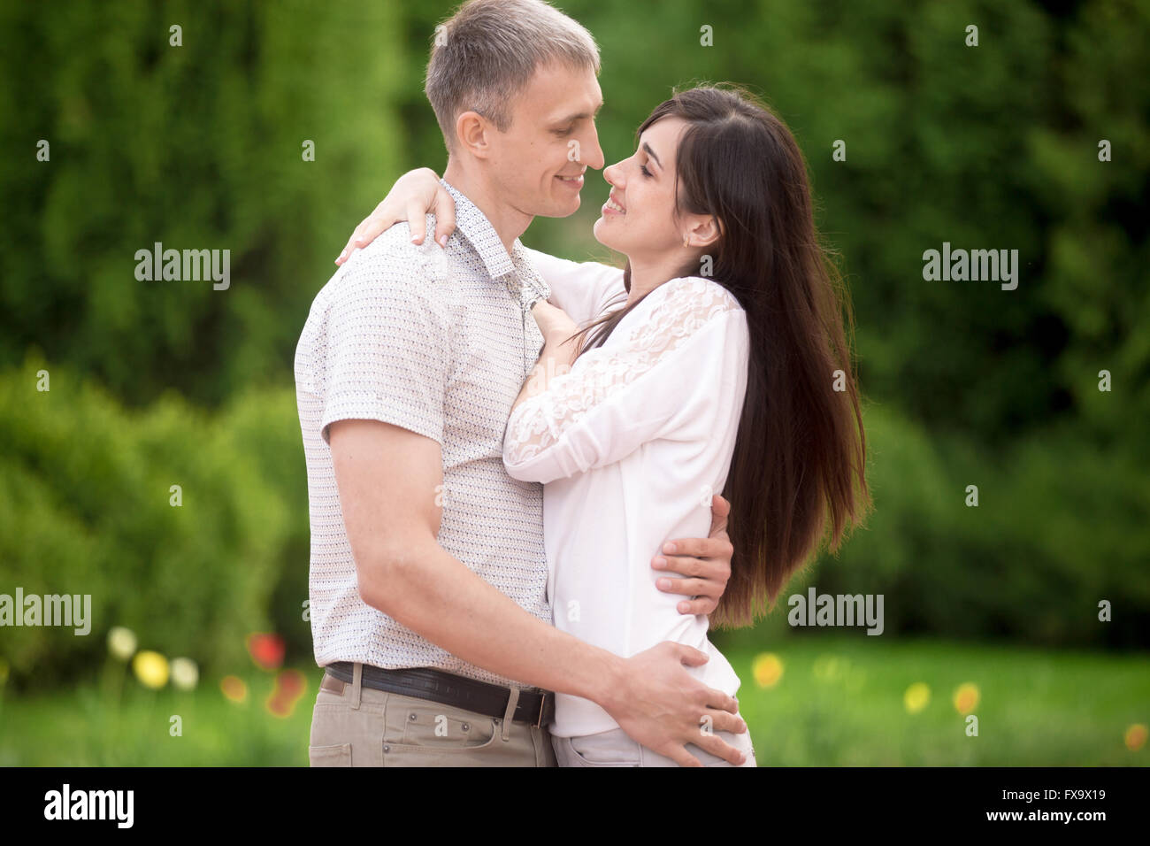 Liebespaar auf ein Datum im Park, von Angesicht zu Angesicht stehen junge Mann zärtlich umarmt seine glücklich lächelnde Freundin Stockfoto