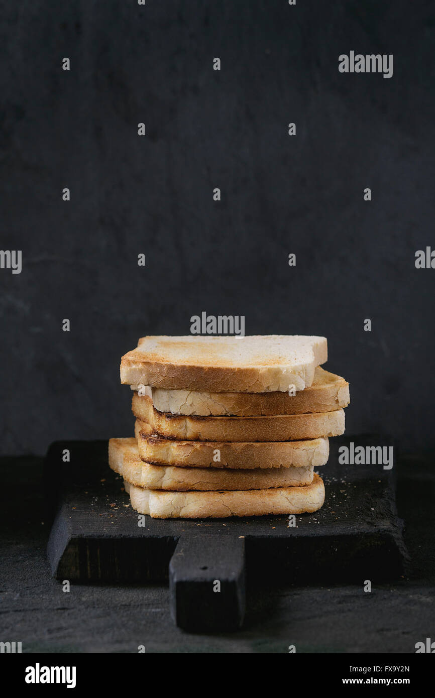 Haufen von frischem Toast Brot auf schwarzen Holzbrett über schwarz strukturierten Hintergrund. Stockfoto