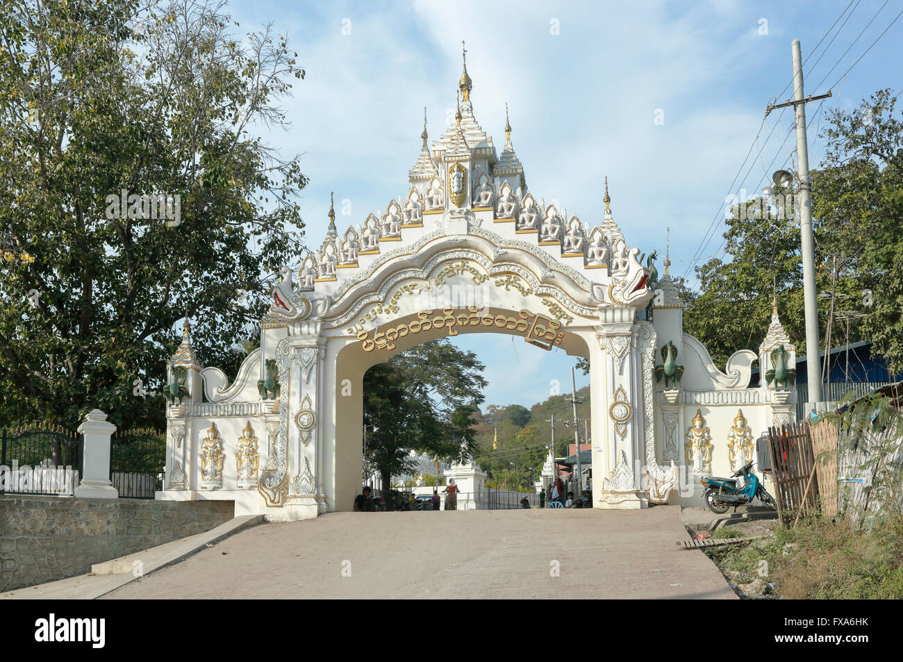 In der Regel reich verzierte Eingangstor die Kyauk Taw Gyi Pagode am Fuße des Mandalay Hill, Mandalay, Myanmar (Burma) an einem sonnigen Tag mit blauem Himmel Stockfoto
