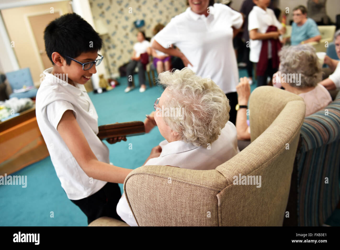 Schulkinder besuchen die Senioren in einem Pflegeheim um gute Beziehungen zwischen den Generationen zu fördern Stockfoto