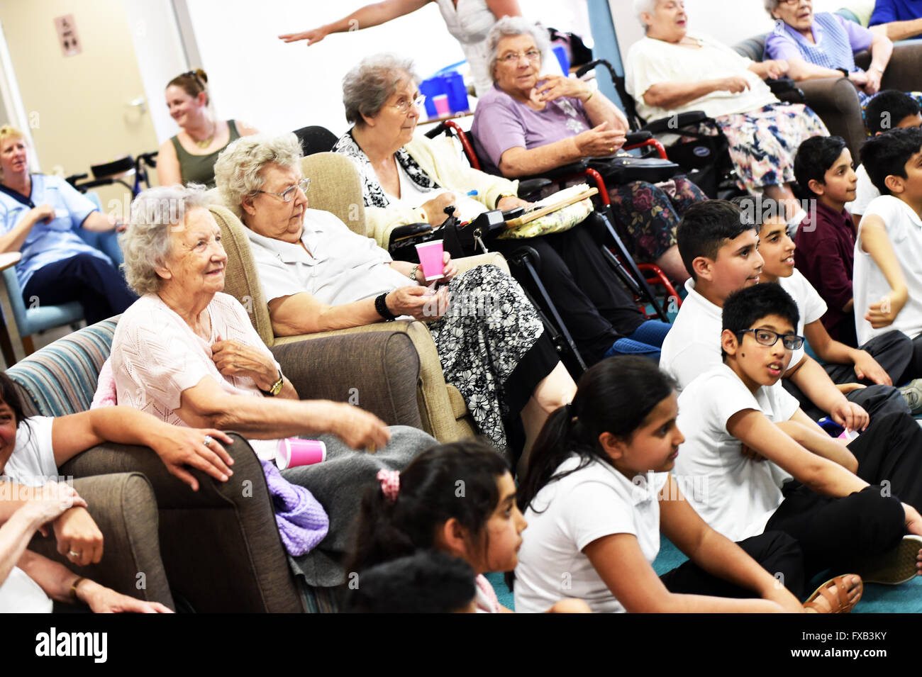 Schulkinder besuchen ein Senioren-Pflegeheim Generationenbeziehungen zu entwickeln. Stockfoto
