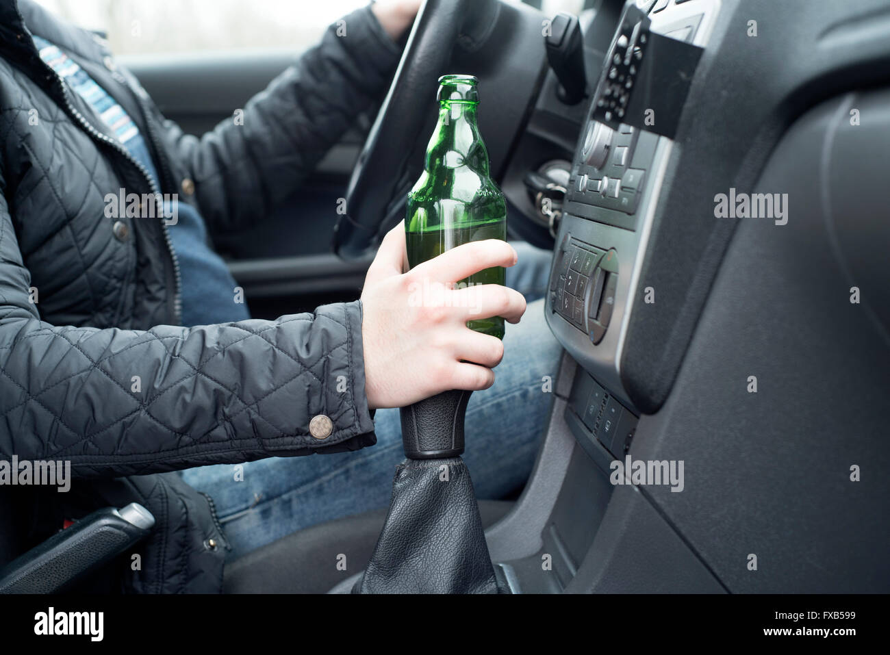 ein Bild eines jungen Mannes, das Trinken von Alkohol während der Fahrt Stockfoto
