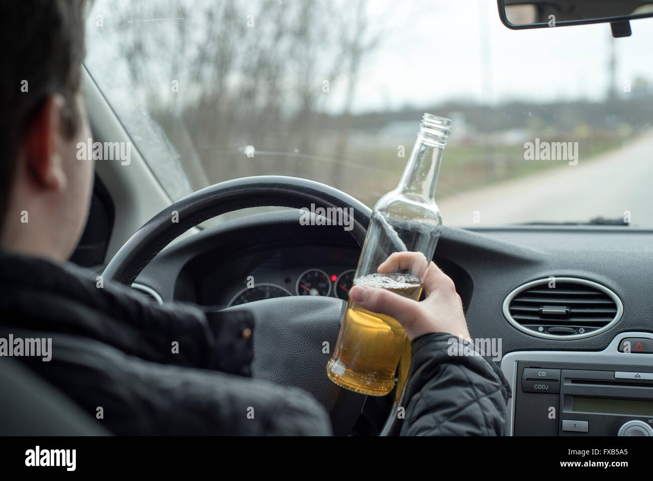 ein Bild eines jungen Mannes, das Trinken von Alkohol während der Fahrt Stockfoto