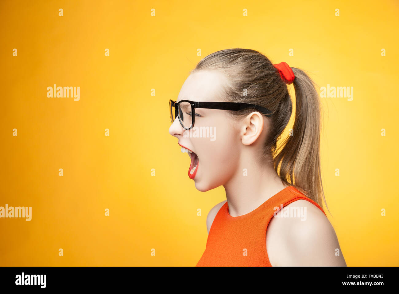 Strenge Frau schreiend auf orangem Hintergrund Stockfoto